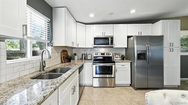 2829 Illinois Ave, Colorado Springs, CO 80907 - kitchen with appliances with stainless steel finishes, white cabinets, light tile patterned floors, backsplash, and healthy amount of natural light