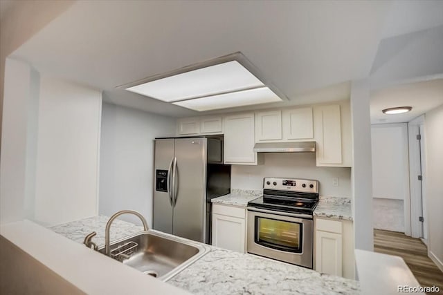 kitchen with light stone counters, light hardwood / wood-style floors, appliances with stainless steel finishes, and sink