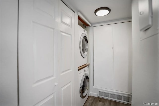 clothes washing area with dark wood-type flooring and stacked washing maching and dryer