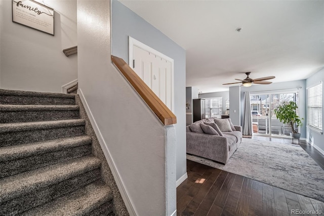 staircase with ceiling fan, baseboards, and wood finished floors