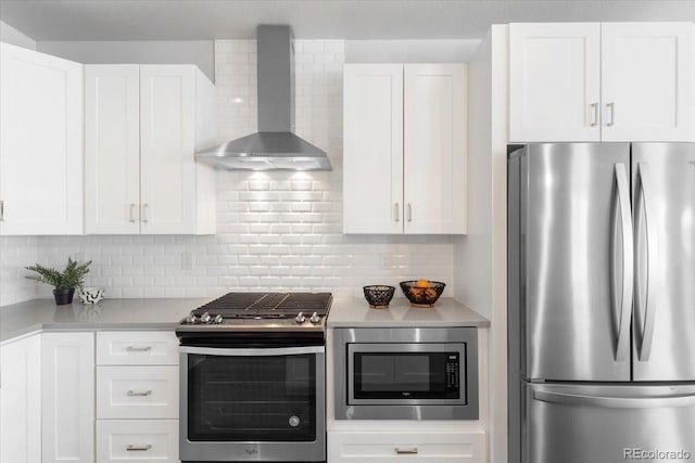 kitchen featuring light countertops, wall chimney exhaust hood, tasteful backsplash, and appliances with stainless steel finishes