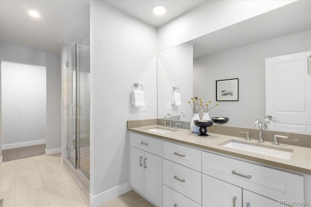 bathroom with a sink, baseboards, a stall shower, and double vanity