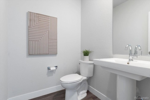 bathroom with a sink, baseboards, toilet, and wood finished floors