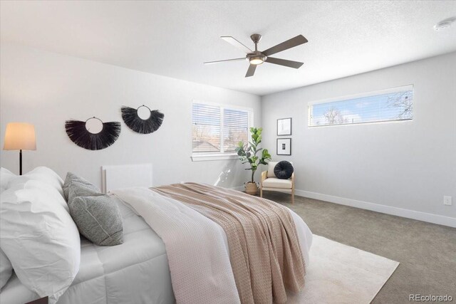 bedroom featuring a textured ceiling, baseboards, carpet floors, and ceiling fan