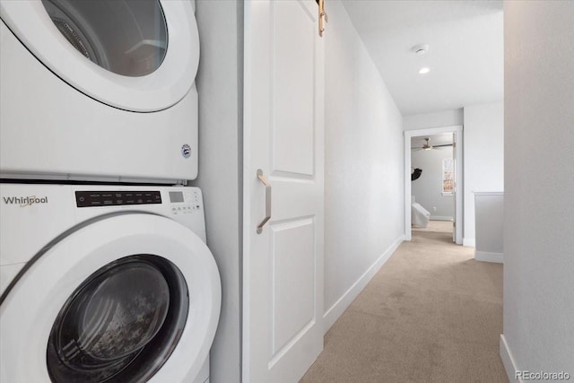 laundry room featuring laundry area, stacked washer / dryer, carpet flooring, and baseboards