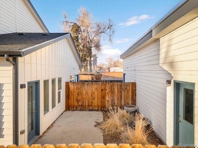 exterior space featuring a patio area, roof with shingles, and fence