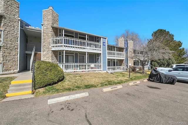 view of property with stairs and uncovered parking