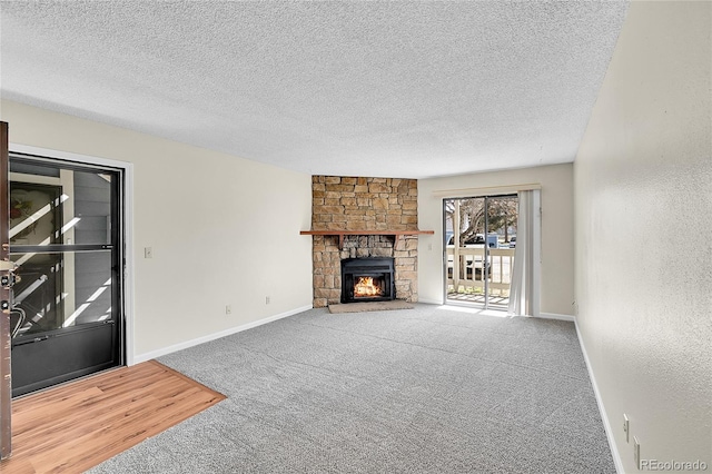 unfurnished living room featuring baseboards, carpet floors, a stone fireplace, a textured ceiling, and a textured wall