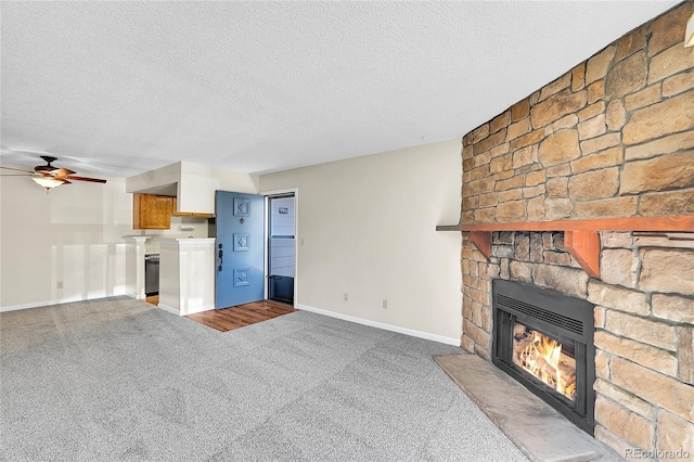 unfurnished living room with carpet, a stone fireplace, a ceiling fan, and a textured ceiling