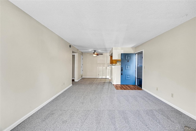 unfurnished living room with carpet flooring, a ceiling fan, baseboards, and a textured ceiling