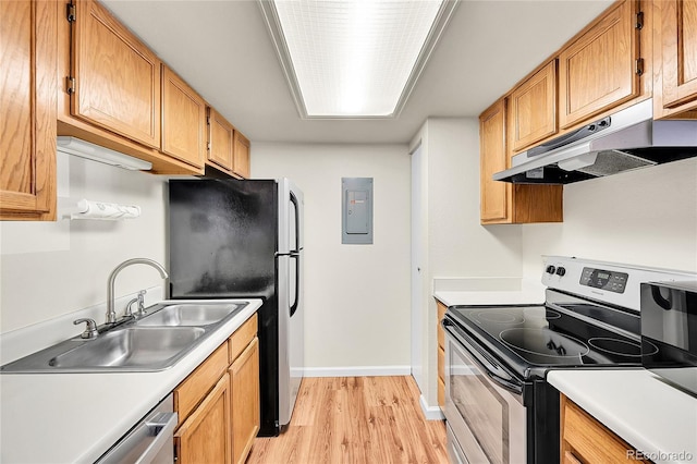 kitchen featuring light wood-type flooring, under cabinet range hood, electric panel, a sink, and appliances with stainless steel finishes