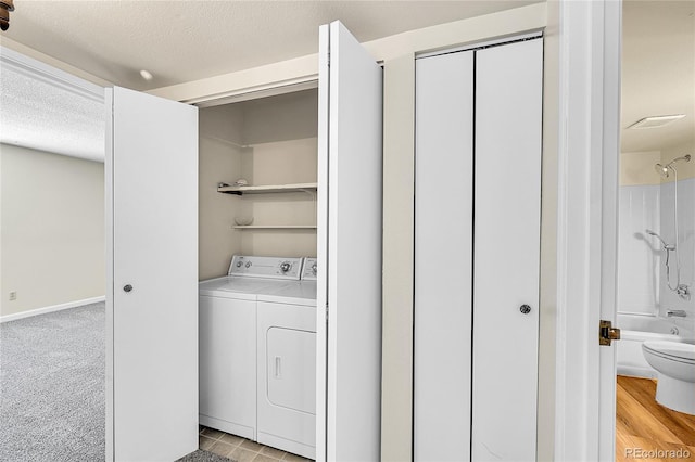 laundry room featuring baseboards, laundry area, a textured ceiling, light colored carpet, and independent washer and dryer