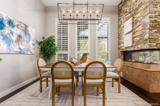 dining space with wood-type flooring and a stone fireplace