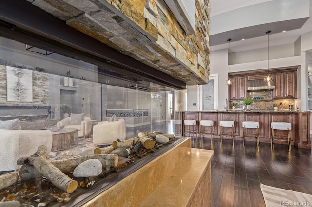 interior space with backsplash, sink, range hood, and hardwood / wood-style flooring