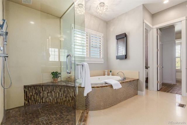 bathroom featuring tile patterned flooring, shower with separate bathtub, and an inviting chandelier