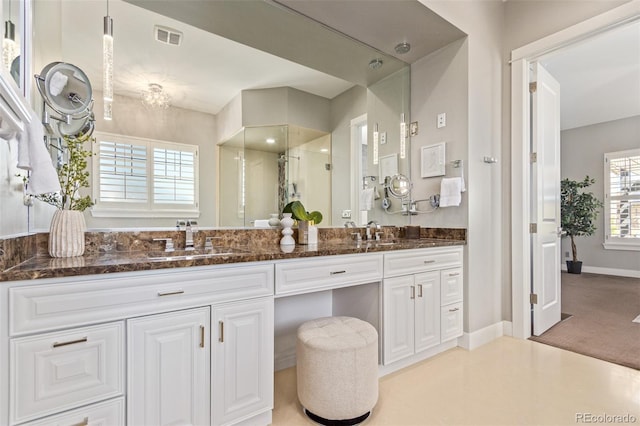 bathroom featuring a shower with door and vanity