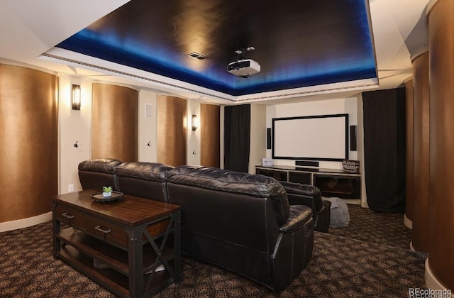 home theater featuring a tray ceiling and dark carpet