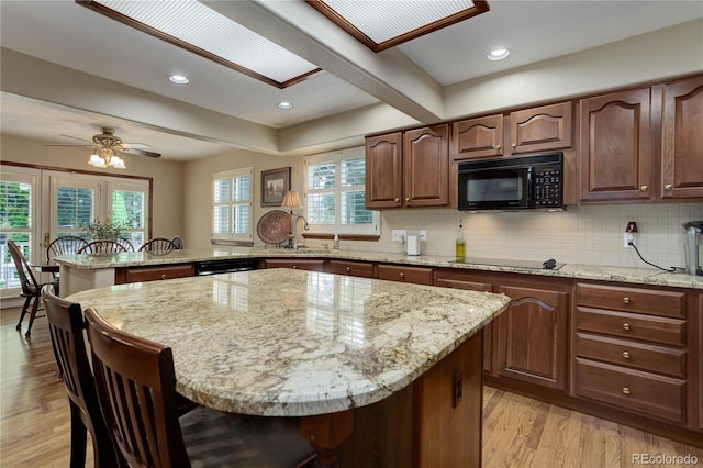10032 Astoria Ct, Lone Tree, CO 80124 - kitchen with black appliances, a breakfast bar area, a peninsula, light stone countertops, and recessed lighting
