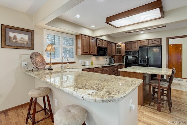 10032 Astoria Ct, Lone Tree, CO 80124 - kitchen with black appliances, a breakfast bar, a peninsula, decorative backsplash, and light stone countertops