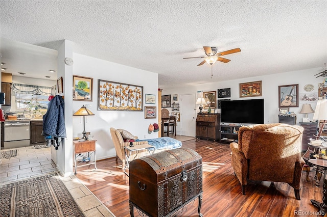 living room with light wood-style flooring, a textured ceiling, and a ceiling fan