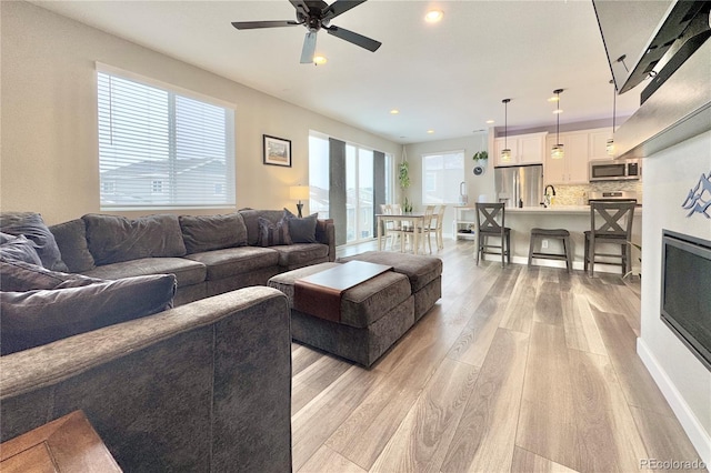 living room with ceiling fan, sink, and light hardwood / wood-style flooring