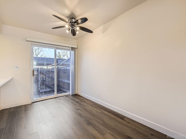 spare room featuring dark wood-style floors, ceiling fan, and baseboards