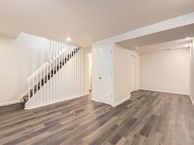 finished basement with baseboards, stairway, and wood finished floors