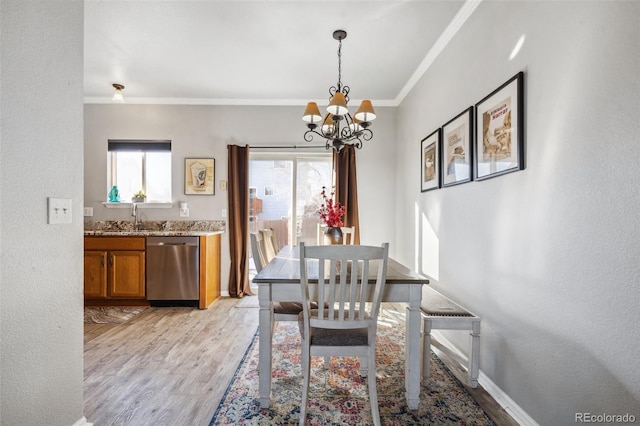 dining space featuring an inviting chandelier, ornamental molding, light hardwood / wood-style flooring, and sink