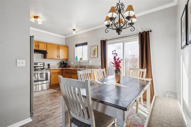 dining room featuring a notable chandelier, light hardwood / wood-style floors, crown molding, and sink