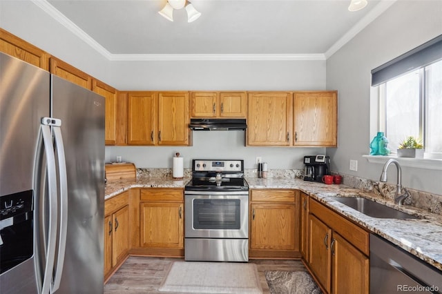 kitchen with appliances with stainless steel finishes, ornamental molding, light stone counters, and sink