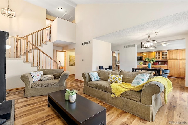 2650 S Vaughn Way Unit B, Aurora, CO 80014 - living area featuring a chandelier, light wood-type flooring, stairway, and high vaulted ceiling