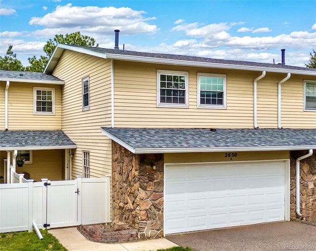2650 S Vaughn Way Unit B, Aurora, CO 80014 - multi unit property featuring a gate, an attached garage, asphalt driveway, stone siding, and roof with shingles