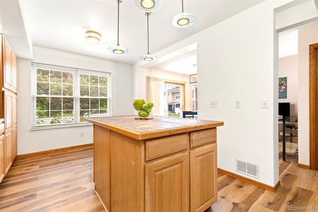 2650 S Vaughn Way Unit B, Aurora, CO 80014 - kitchen featuring baseboards, light wood-style flooring, a kitchen island, hanging light fixtures, and tile counters