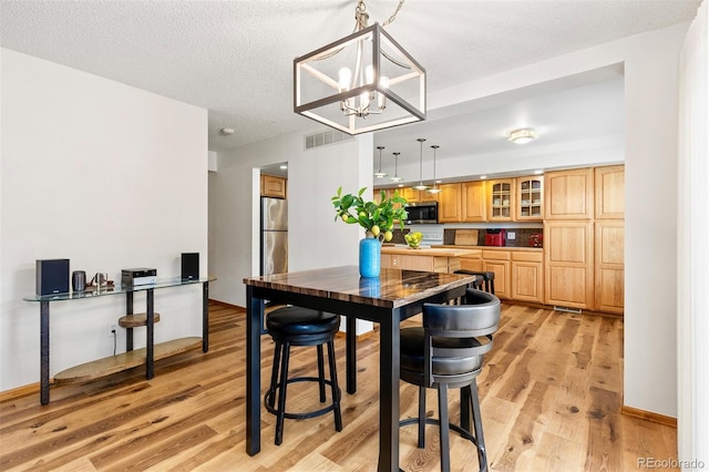 2650 S Vaughn Way Unit B, Aurora, CO 80014 - dining room featuring light wood finished floors, a chandelier, and a textured ceiling