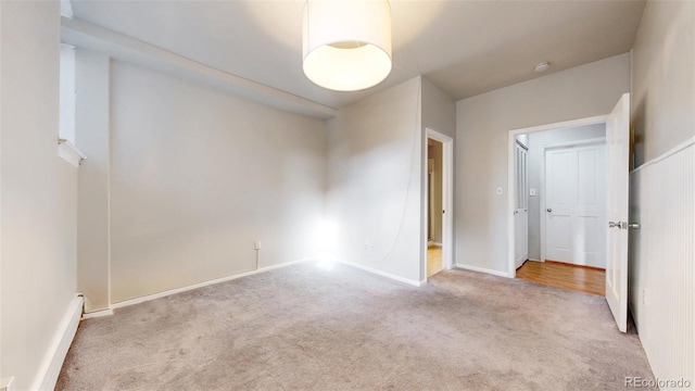 empty room featuring baseboards and light colored carpet