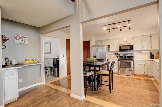 10059 Granite Hill Dr, Parker, CO 80134 - kitchen with light wood-style flooring, baseboards, white cabinetry, light countertops, and appliances with stainless steel finishes