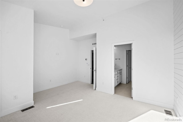 unfurnished bedroom with connected bathroom and light carpet