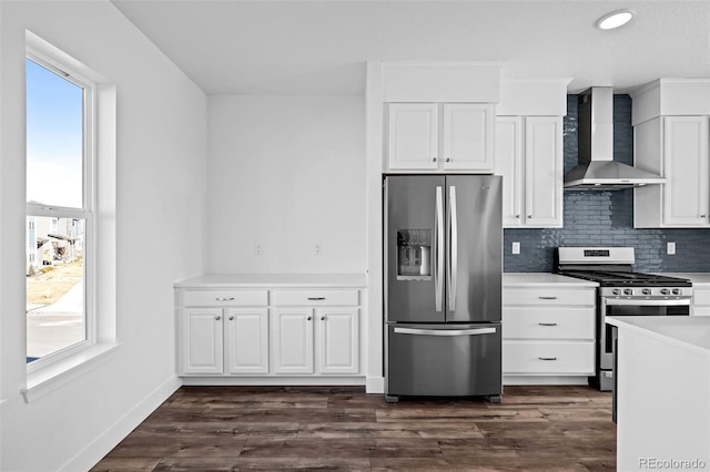 kitchen featuring wall chimney exhaust hood, dark hardwood / wood-style floors, stainless steel appliances, decorative backsplash, and white cabinets