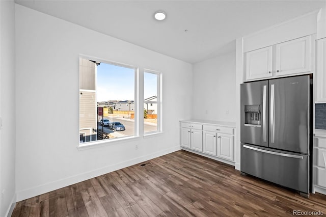 kitchen with dark hardwood / wood-style flooring, stainless steel fridge, and white cabinets