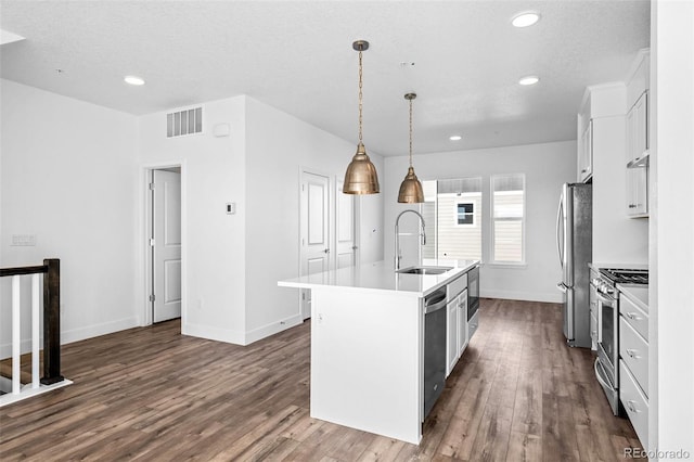 kitchen featuring sink, decorative light fixtures, appliances with stainless steel finishes, an island with sink, and white cabinets