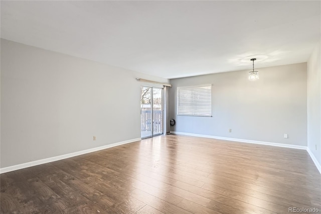 spare room featuring dark hardwood / wood-style floors and a notable chandelier