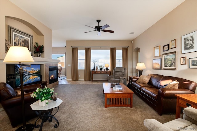 carpeted living room with a tile fireplace and ceiling fan