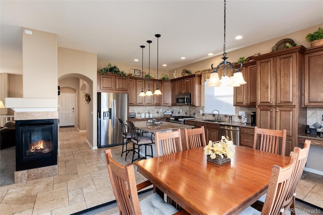 dining room with sink, a notable chandelier, and a multi sided fireplace