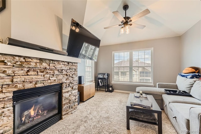 carpeted living room featuring ceiling fan, vaulted ceiling, and a stone fireplace