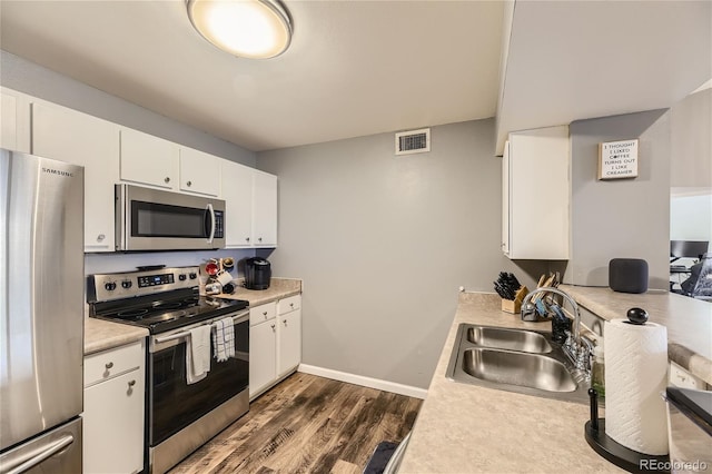 kitchen featuring dark wood-type flooring, sink, white cabinets, and stainless steel appliances