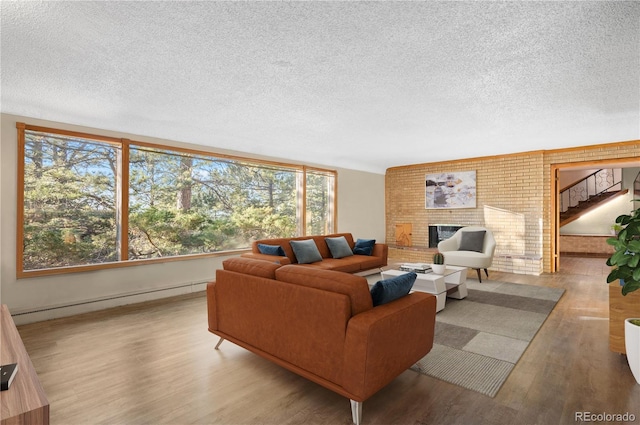 living room featuring a baseboard radiator, a fireplace, light hardwood / wood-style floors, and a textured ceiling