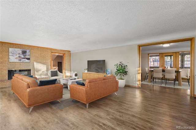 living room with a brick fireplace, hardwood / wood-style flooring, and a textured ceiling