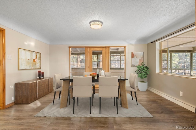 dining space featuring wood-type flooring, plenty of natural light, and a textured ceiling