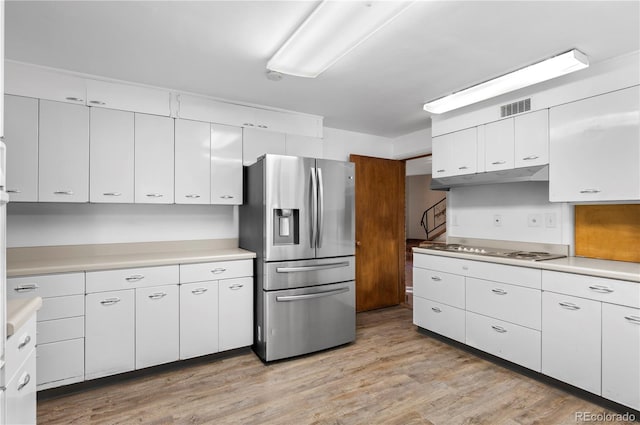 kitchen with white cabinetry, stainless steel fridge, light wood-type flooring, and white gas cooktop