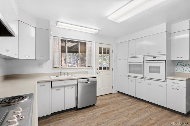 kitchen with sink, stainless steel dishwasher, oven, and white cabinets